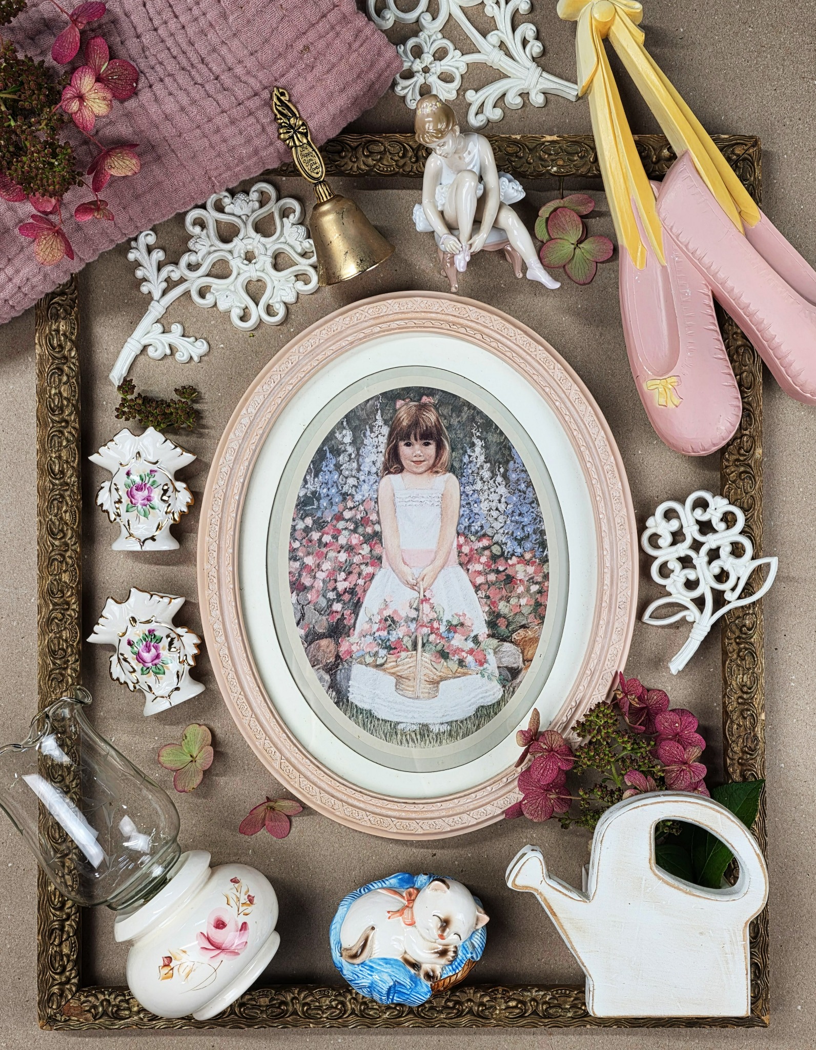 Vintage pink and floral décor arranged around a framed picture, including ballet slippers, a bell, and ceramic pieces